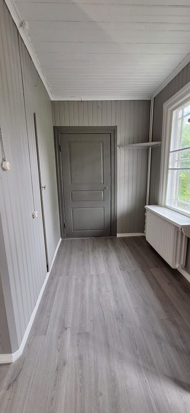 Tak-, vägg-, dörr målning & golvläggning vinyl Ljust rum med grå väggar, en dörr, fönster och ett radiator.